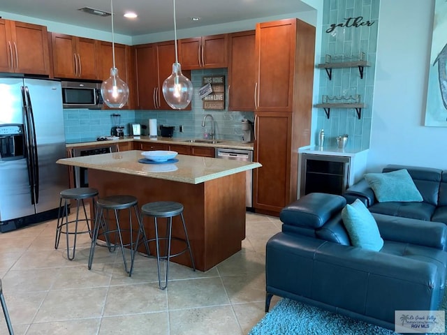 kitchen featuring appliances with stainless steel finishes, sink, decorative backsplash, hanging light fixtures, and a center island