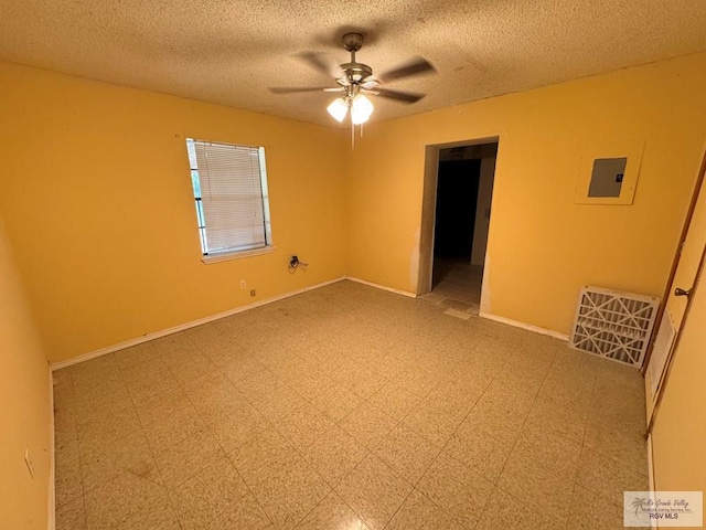 empty room with a textured ceiling, electric panel, and ceiling fan