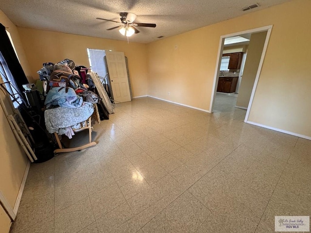 empty room with ceiling fan and a textured ceiling