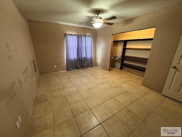 unfurnished bedroom featuring ceiling fan, light tile patterned floors, and a closet