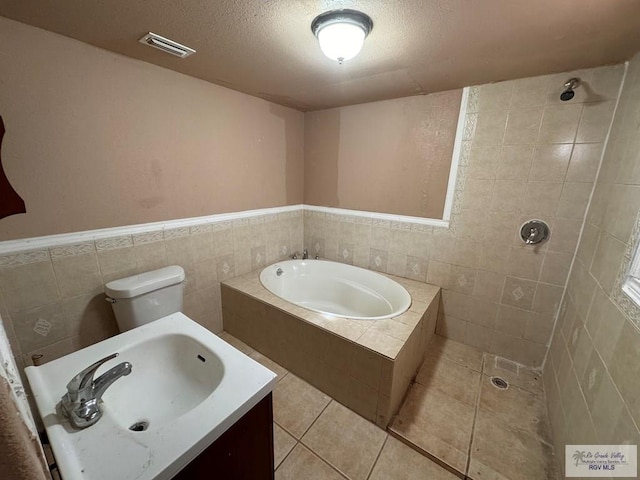 full bathroom featuring tile patterned flooring, a textured ceiling, shower with separate bathtub, toilet, and tile walls