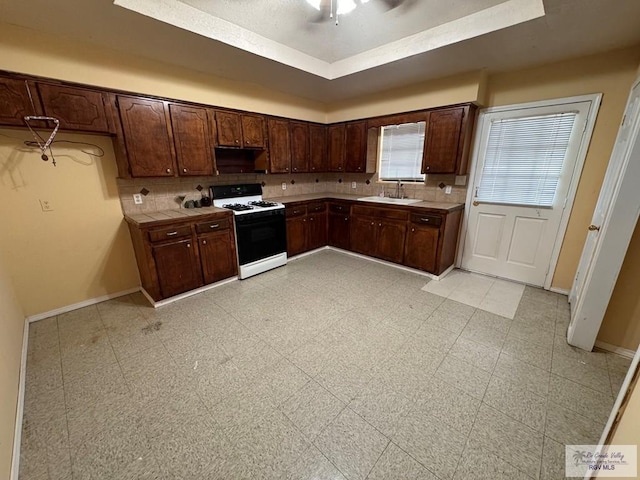 kitchen featuring white range, tasteful backsplash, dark brown cabinetry, and sink