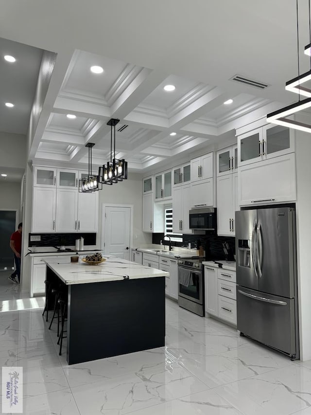 kitchen featuring appliances with stainless steel finishes, a center island, decorative light fixtures, and white cabinetry