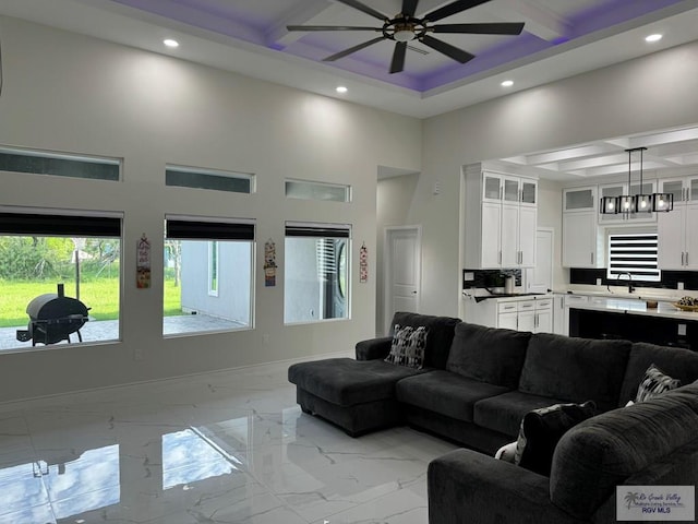 living room featuring ceiling fan, sink, and a high ceiling