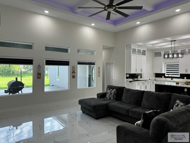 living room with beamed ceiling, a high ceiling, ceiling fan, and sink