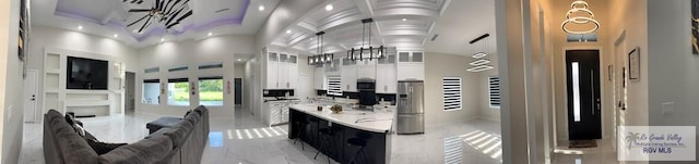 kitchen featuring appliances with stainless steel finishes, a towering ceiling, and white cabinetry