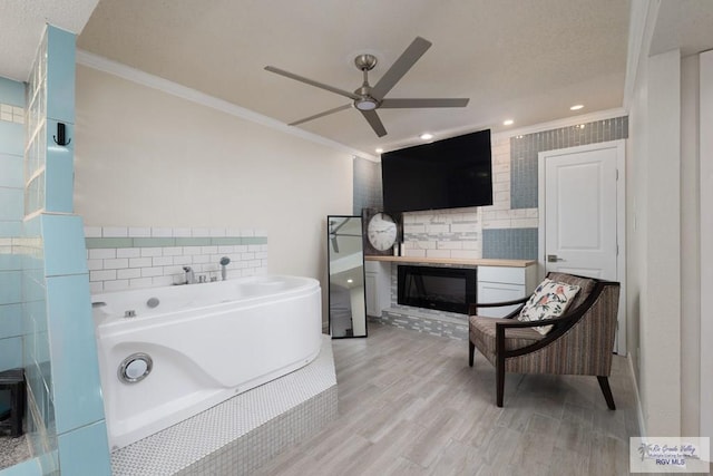 1302 Harbor Island Dr, Port Isabel, TX 78526 - full bath with ornamental molding, a ceiling fan, a garden tub, wood finished floors, and a glass covered fireplace