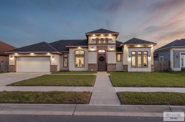 view of front facade with stucco siding, a front lawn, fence, concrete driveway, and an attached garage