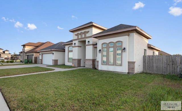 view of front facade with stucco siding, driveway, a front lawn, fence, and an attached garage