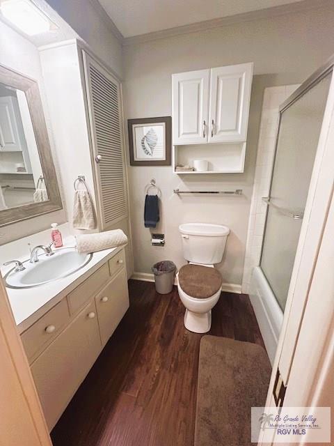 full bathroom with hardwood / wood-style floors, vanity, toilet, and combined bath / shower with glass door