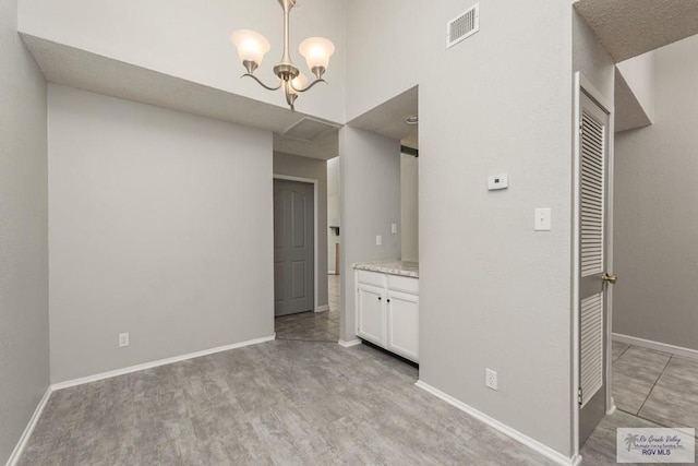 unfurnished dining area featuring a high ceiling and an inviting chandelier