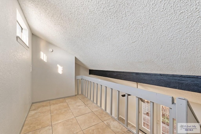 hall with light tile patterned floors and vaulted ceiling