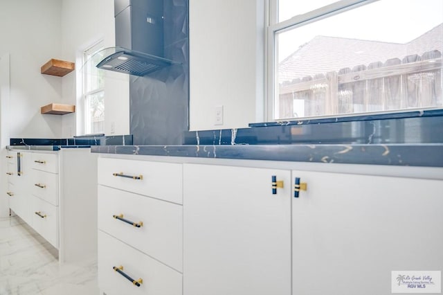 kitchen featuring white cabinetry, a healthy amount of sunlight, and wall chimney range hood