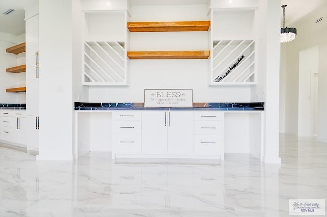 kitchen featuring a chandelier, white cabinetry, and pendant lighting