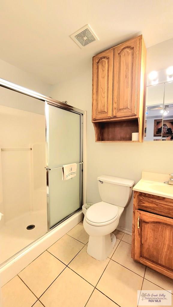 bathroom with toilet, vanity, tile patterned floors, and walk in shower