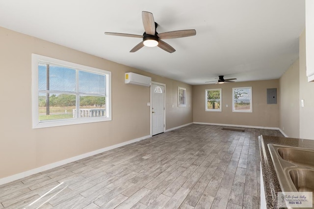 unfurnished living room with a wall mounted air conditioner, ceiling fan, a healthy amount of sunlight, and light hardwood / wood-style floors