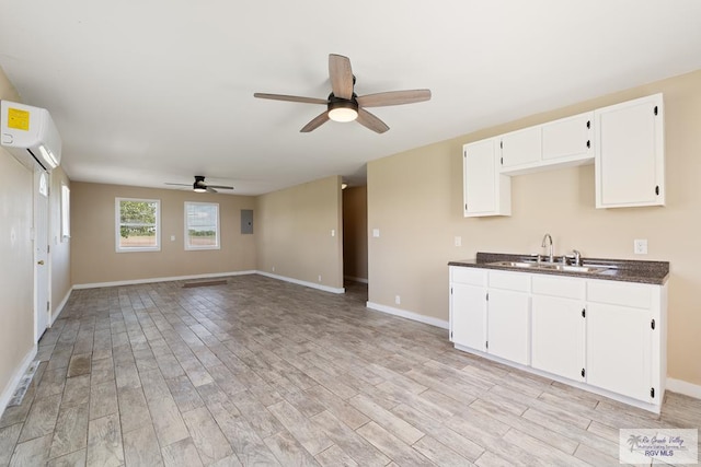 kitchen featuring a wall mounted air conditioner, sink, ceiling fan, light wood-type flooring, and white cabinetry