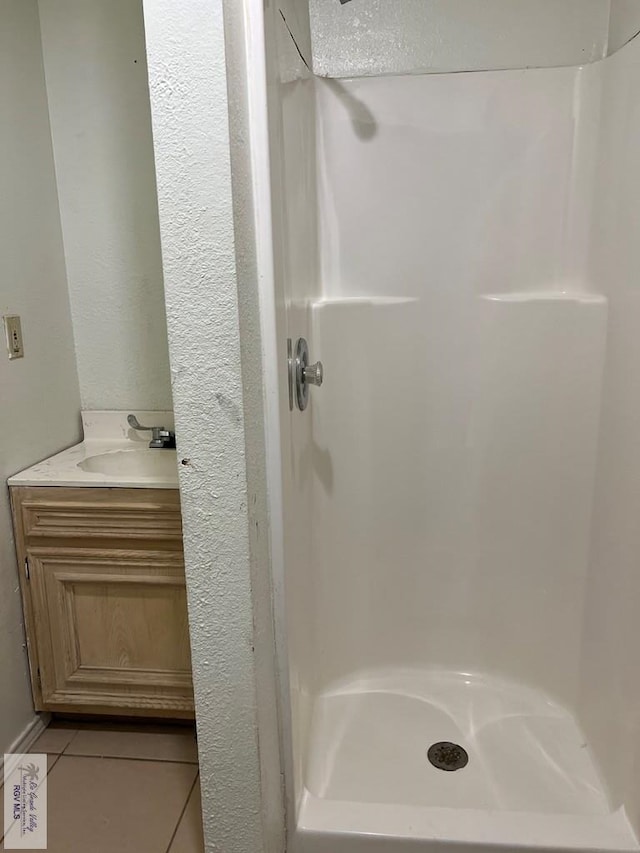 bathroom featuring tile patterned flooring, vanity, and walk in shower