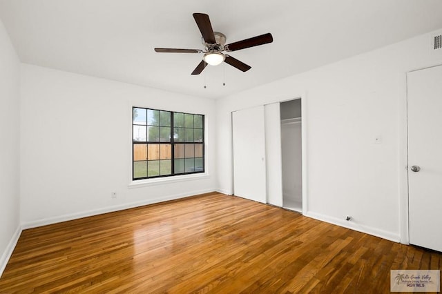 unfurnished bedroom with wood-type flooring, a closet, and ceiling fan