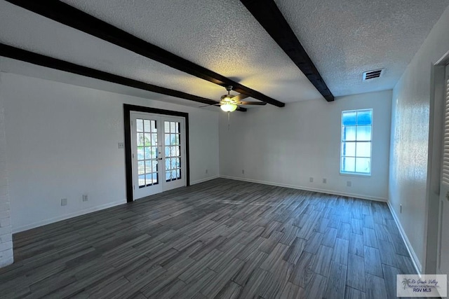 empty room with beamed ceiling, dark hardwood / wood-style flooring, a textured ceiling, and a wealth of natural light