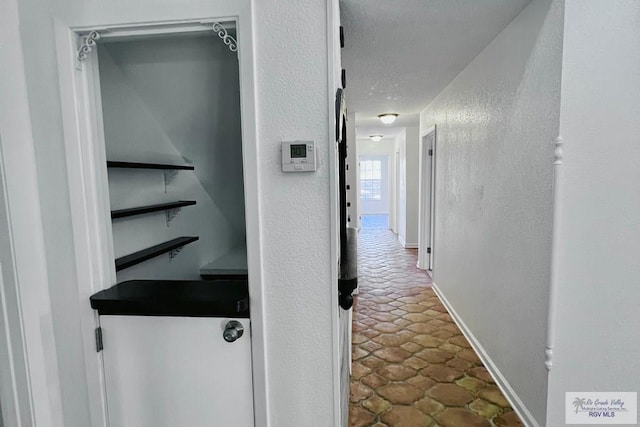 hall featuring a textured ceiling and tile patterned floors