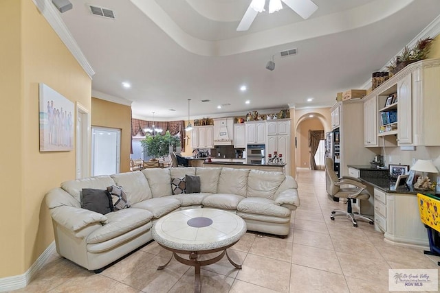 tiled living room with ceiling fan with notable chandelier and crown molding