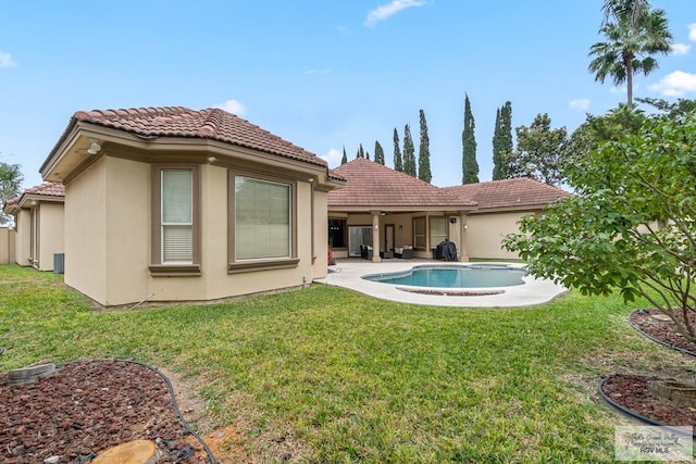 rear view of house featuring a lawn and a patio