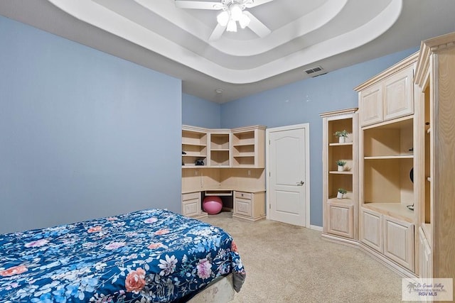 carpeted bedroom with a tray ceiling and ceiling fan