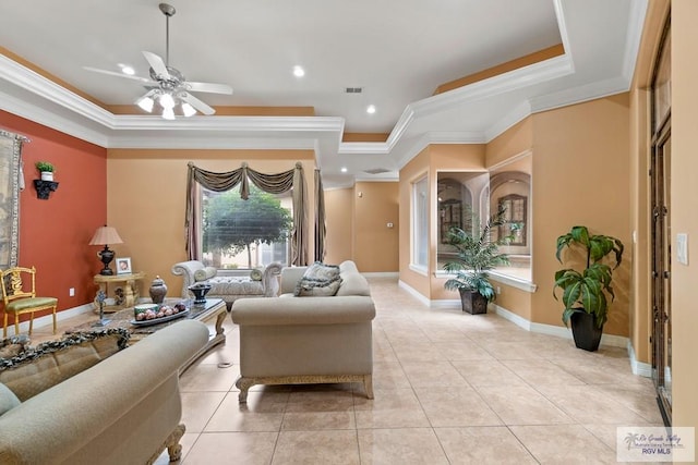 living room with ceiling fan, a raised ceiling, ornamental molding, and light tile patterned floors