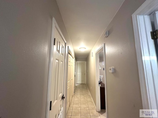 corridor with light tile patterned floors and baseboards