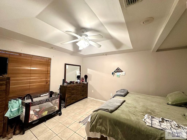 bedroom featuring a tray ceiling, visible vents, light tile patterned flooring, and a ceiling fan