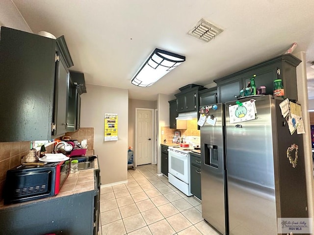 kitchen with light tile patterned floors, visible vents, white range with electric cooktop, a sink, and stainless steel fridge