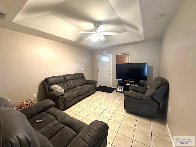 living area featuring visible vents, a ceiling fan, a tray ceiling, light tile patterned floors, and baseboards