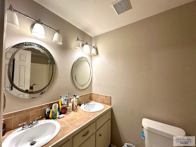 full bathroom featuring a sink, visible vents, toilet, and double vanity