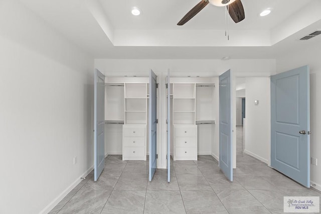 unfurnished bedroom with ceiling fan and a tray ceiling