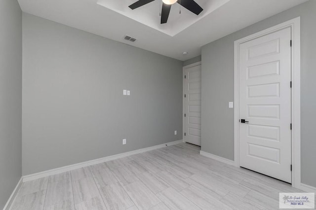 unfurnished bedroom featuring a raised ceiling and ceiling fan