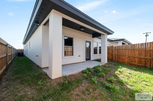 rear view of house featuring a patio, central AC, and a lawn