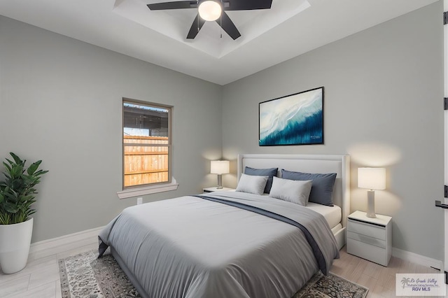 bedroom with ceiling fan and a raised ceiling