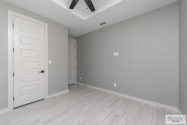 unfurnished bedroom featuring ceiling fan and a tray ceiling