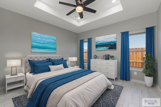 bedroom featuring a raised ceiling and ceiling fan