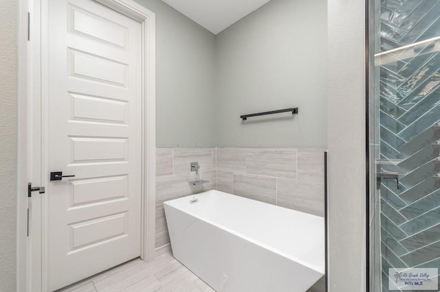 bathroom featuring a bath and tile walls