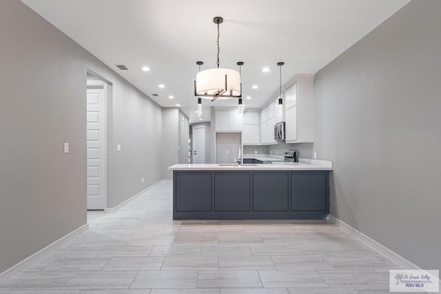 kitchen with pendant lighting, sink, stainless steel appliances, white cabinets, and kitchen peninsula