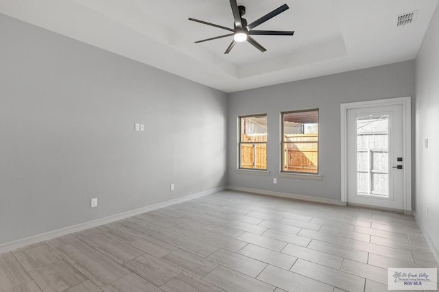 empty room featuring ceiling fan and a tray ceiling