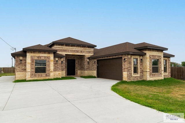 prairie-style house featuring a garage and a front lawn