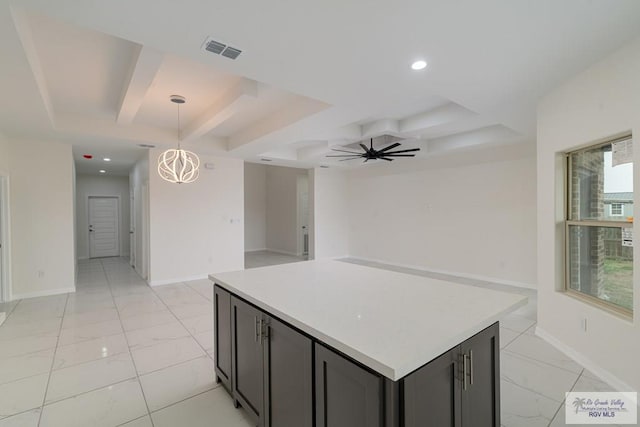 kitchen featuring gray cabinetry, ceiling fan with notable chandelier, a tray ceiling, decorative light fixtures, and a kitchen island