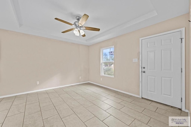 empty room featuring light tile patterned floors, a raised ceiling, and ceiling fan