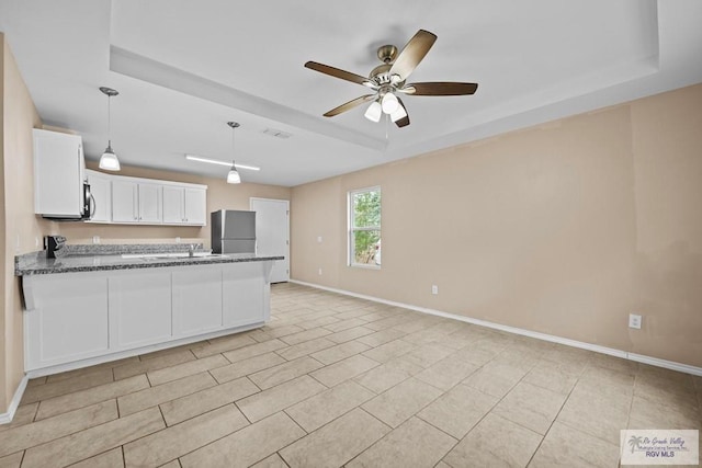 kitchen with white cabinets, refrigerator, and a tray ceiling