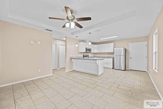 kitchen with a raised ceiling, kitchen peninsula, white cabinets, and appliances with stainless steel finishes