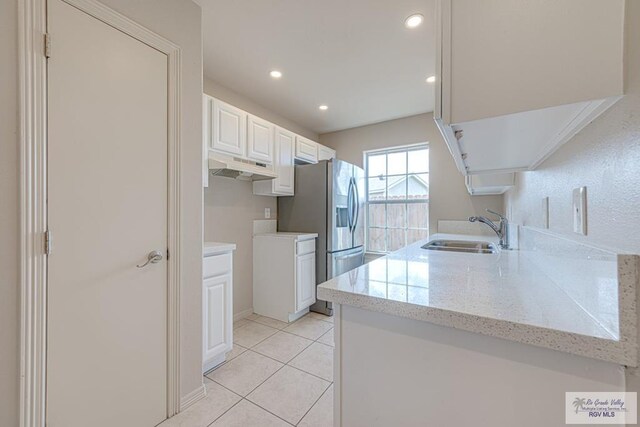 2400 Firenze St, Brownsville, TX 78520 - kitchen with under cabinet range hood, stainless steel fridge with ice dispenser, recessed lighting, white cabinets, and light stone countertops