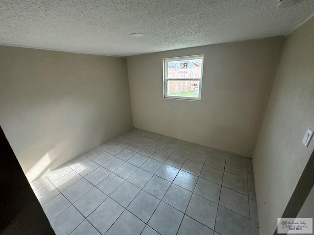 spare room with a textured ceiling and light tile patterned flooring